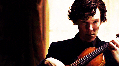 A man playing the violin in front of a window.